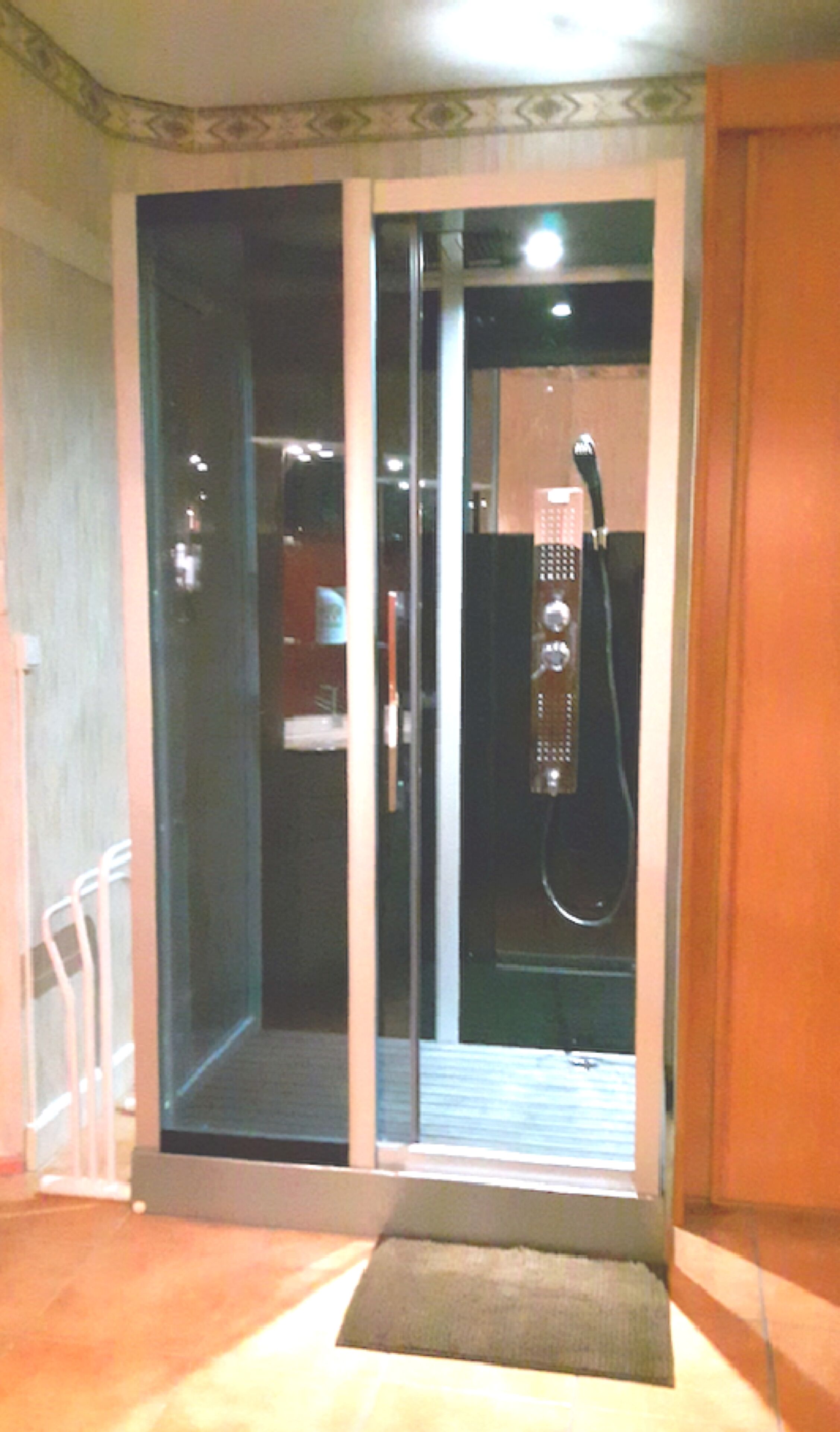 Ein Hotelzimmer mit einer Schiebeglastür, die zu einem Duschbereich führt.