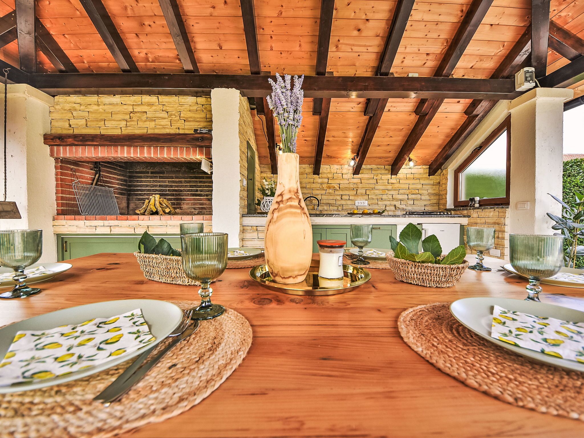 Un espace repas avec une table en bois dressée pour quatre personnes, entouré de murs en briques et surmonté d’un plafond en bois.