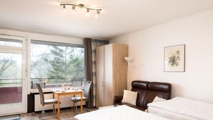 A hotel room with a bed, a desk with a chair, a window with curtains, and a painting on the wall. - Flora und Fauna (B306/B307) by Interhome (Lahnstein (Koblenz))