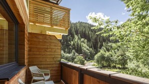 A wooden deck with two white chairs and a table, overlooking a forested valley. - Suite mit 2 SZ & Wellnessbereich by Interhome (Saalbach-Hinterglemm)
