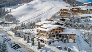 A snow-covered mountain resort with chalet-style buildings, a ski slope, and a clear sky.