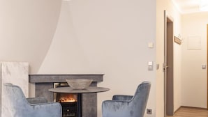A modern living room with a fireplace, two grey chairs, and a round table.
