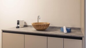 A bathroom with a wooden bowl sink, a faucet, a soap dispenser, and a towel on the counter.
