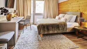 A hotel room with a bed, desk, chair, and a TV mounted on the wall.