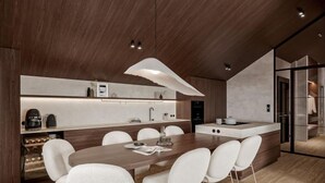 A modern kitchen with a central island, white chairs, and a wooden dining table. - Premium Penthouse mit Sauna by Interhome (Haus)