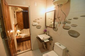 A bathroom with a wooden floor, a white sink, a mirror, a shower, and a toilet.