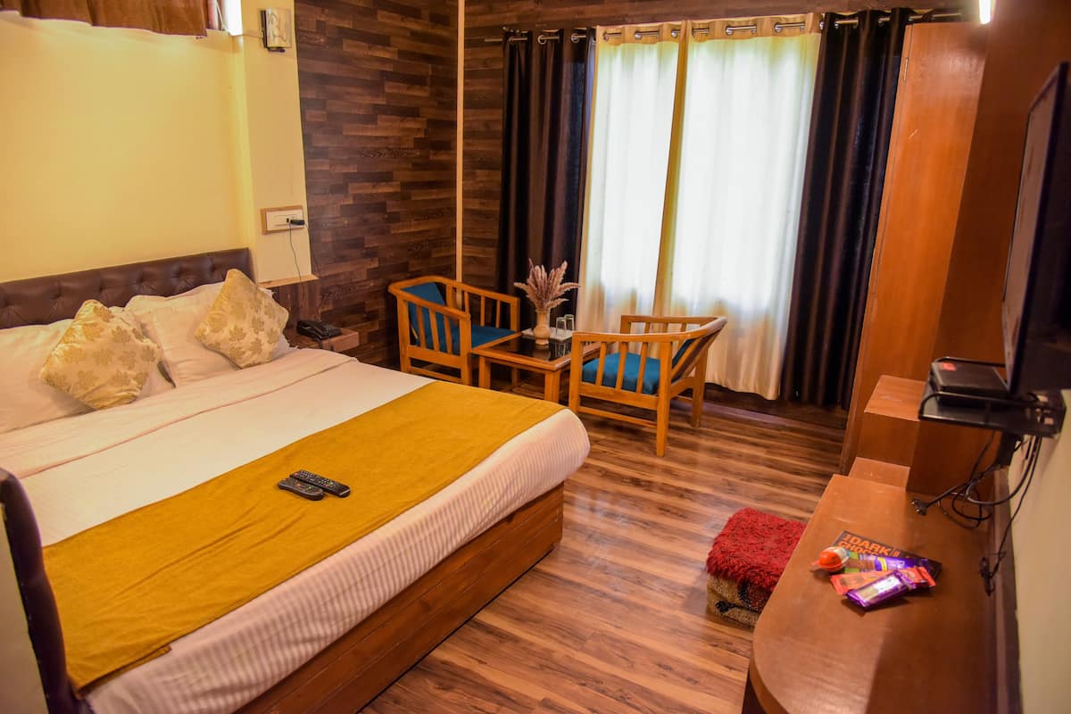Hotellihuone, jossa on suuri sänky, puinen työpöytä, tuoli ja pieni pöytä.