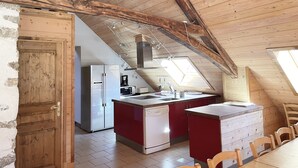 Eine Küche mit Holzbalken, einem Kühlschrank, einem Geschirrspüler und einer kleinen Kochinsel mit Spüle.