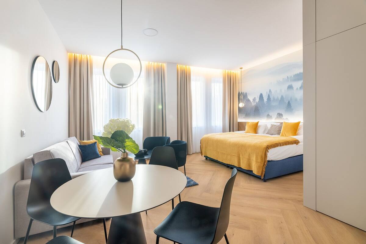 Una habitación de hotel moderna con una cama, una mesa redonda de comedor y un sofá.