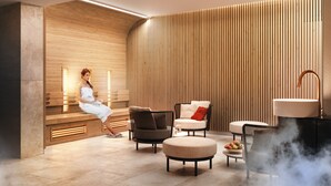 Ein moderner Wellnessbereich mit Holzwand, einer Bank und Sitzgelegenheiten sowie einer Dampfdusche.