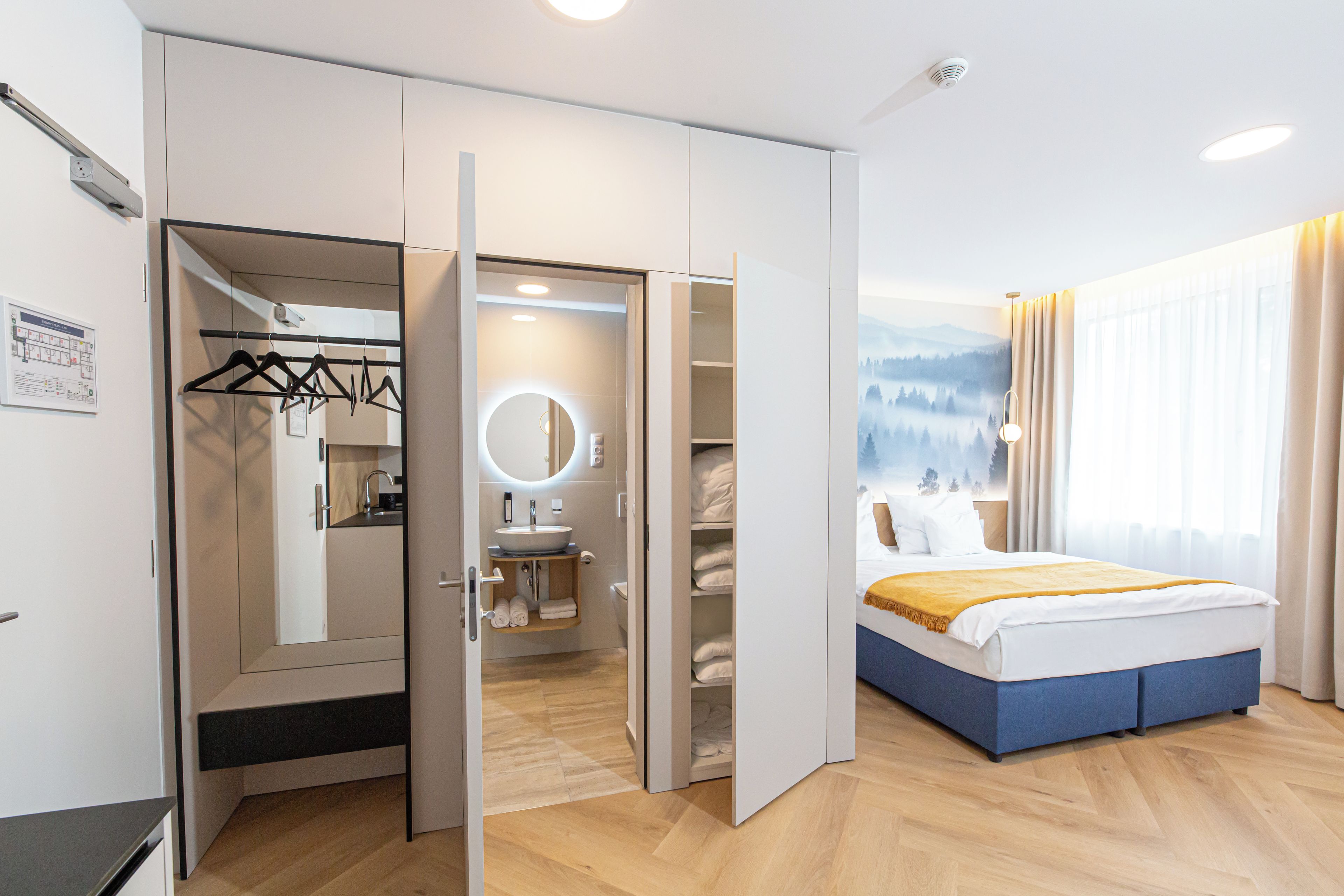 Ein Hotelzimmer mit Bett, Badezimmer und Schrank mit Spiegel.