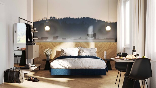Une chambre d’hôtel moderne avec un grand lit, un bureau avec une chaise, une petite table avec une bouteille et des verres, et un mur orné d’un tableau représentant un paysage de montagne.