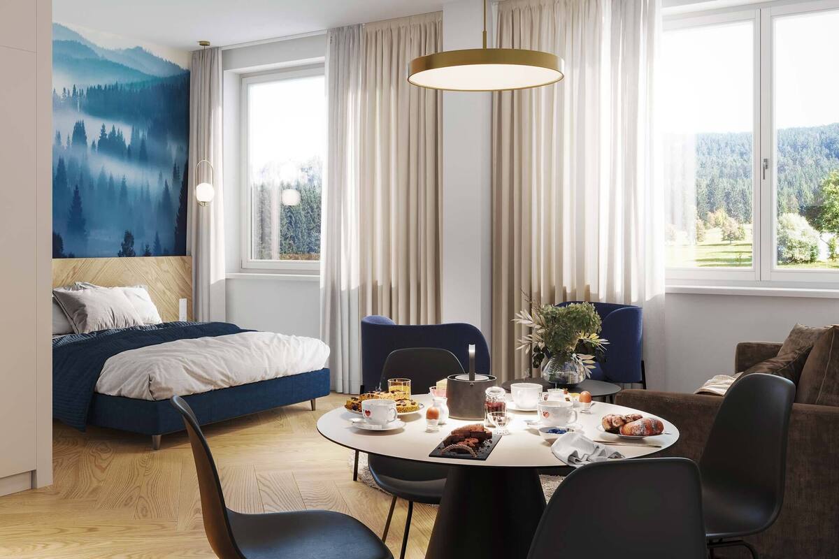 Una habitación de hotel moderna con una cama, una mesa de comedor con productos para el desayuno y vistas al exterior.