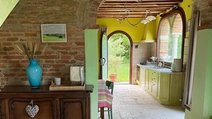 Una cocina rústica con suelo de piedra, armarios de madera y vistas a un jardín a través de un arco.