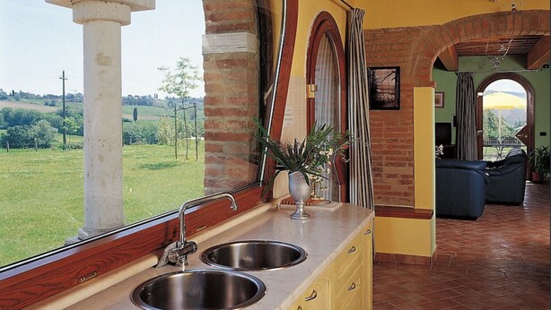 Una cocina con dos lavamanos de acero inoxidable, una planta en maceta y vistas al campo.