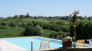 Una piscina con vistas a un paisaje verde y algunas casas a lo lejos.
