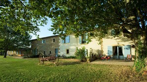 A rustic stone building with a large tree in front, a wooden cart, and outdoor seating. - NICE PROVENCALE HOUSE 4 pers country garden swimming pool SPA playground (Grans)