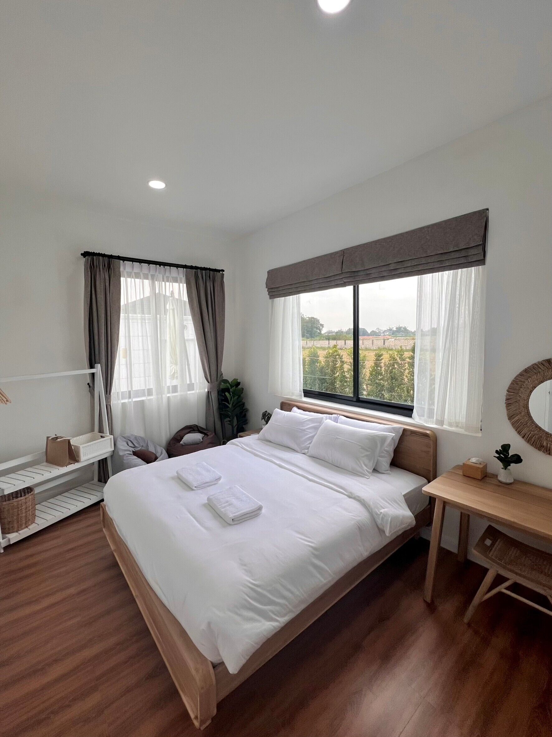 Un dormitorio ordenado con una cama grande, mesitas de noche, un escritorio y una ventana con cortinas.