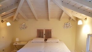 A bedroom with a bed, bedside tables, and a ceiling with exposed beams. - Private Pool in Cottage (POROS)
