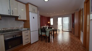 A kitchen with a refrigerator, stove, and cabinets. There is a dining table with chairs and a window with curtains. - DON PACO  (2 BEDROOMS) (Benidorm)