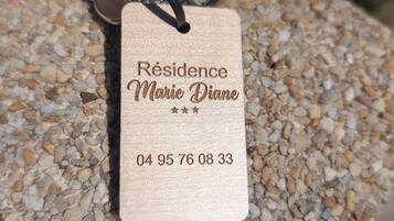 A tag with 'Résidence Marie Diane' and a phone number on a pebble-textured surface.