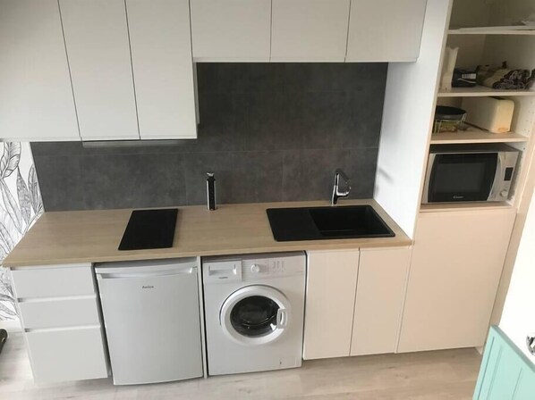 A compact kitchen with a dishwasher, washing machine, and two sinks.