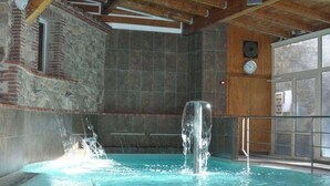 An indoor swimming pool with a waterfall feature, stone walls, and a wooden ceiling. - Brand new "jungle" studio - panoramic view - parking - city center (Font-Romeu-Odeillo-Via)