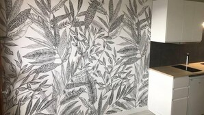A kitchen with a white cabinet and a wall with a detailed black and white botanical mural. - Brand new "jungle" studio - panoramic view - parking - city center (Font-Romeu-Odeillo-Via)