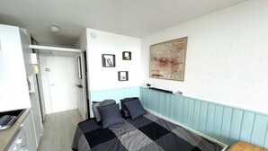 A room with a bed, a map on the wall, a washing machine, and a small table. - Brand new "jungle" studio - panoramic view - parking - city center (Font-Romeu-Odeillo-Via)