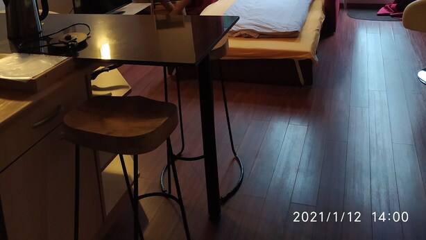 Ein Zimmer mit Bett, Schreibtisch, Stuhl, Bücherregal und Deckenventilator.