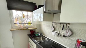 Cuina pràctica amb taulell negre, rentaplat de superfície inoxidable i forn integrat.