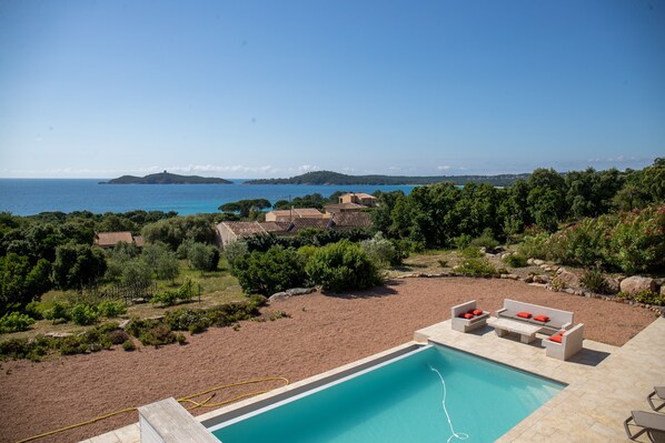 Une piscine avec vue sur la mer et les collines.