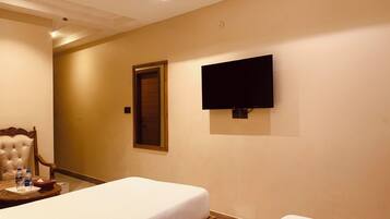 Habitación de hotel con dos camas, un televisor montado en la pared y una puerta al fondo.