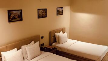 A hotel room with two beds, a nightstand, and three framed pictures on the wall.