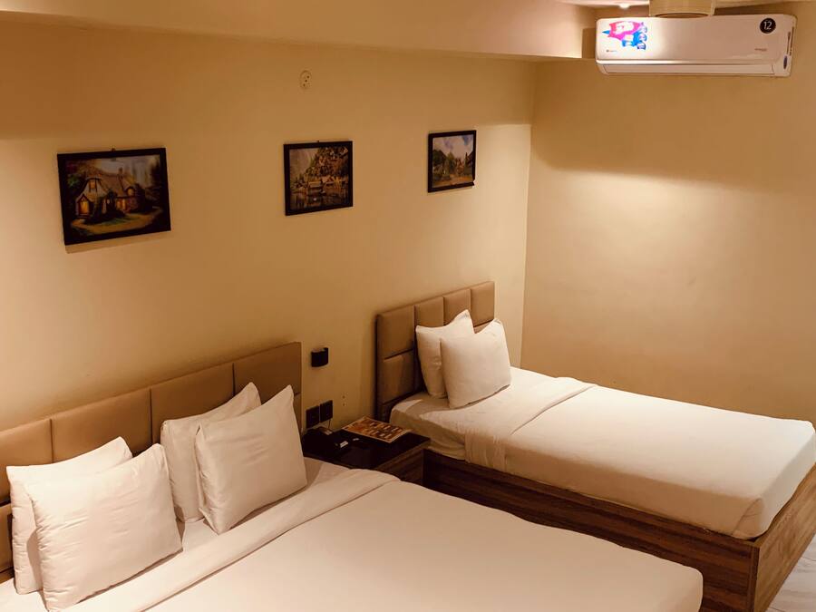 A hotel room with two beds, a nightstand, and three framed pictures on the wall.