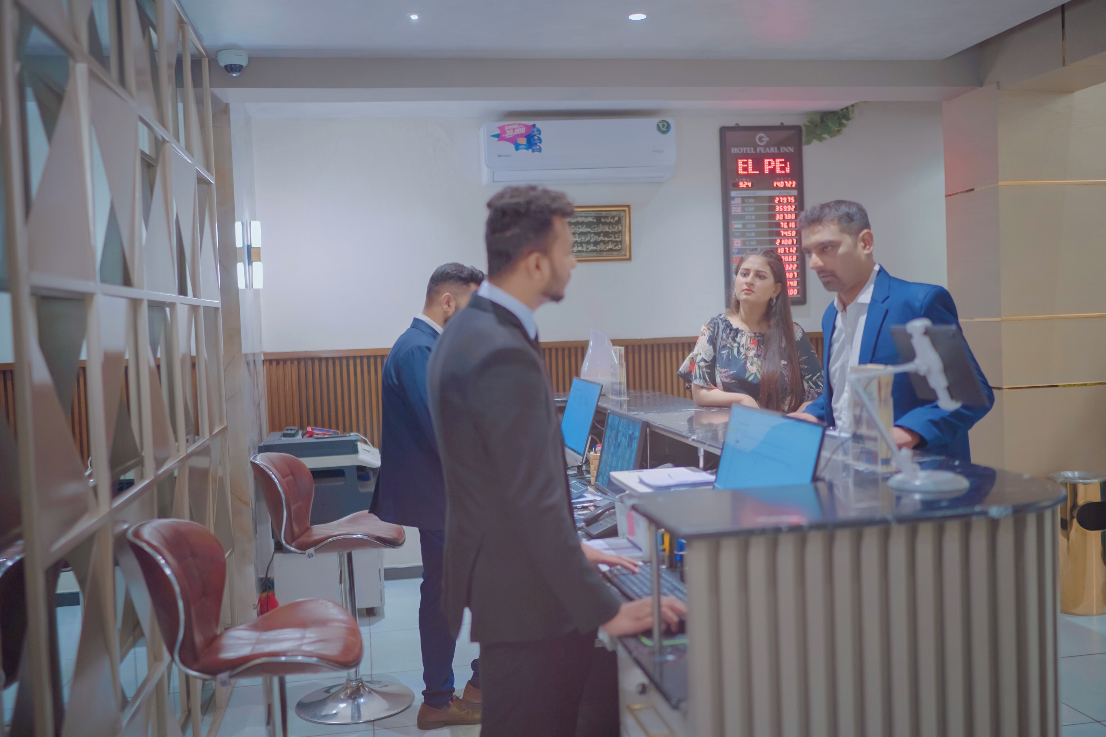 Een hotel receptie met een balie, zitplaatsen en een wandgemonteerde airconditioning.