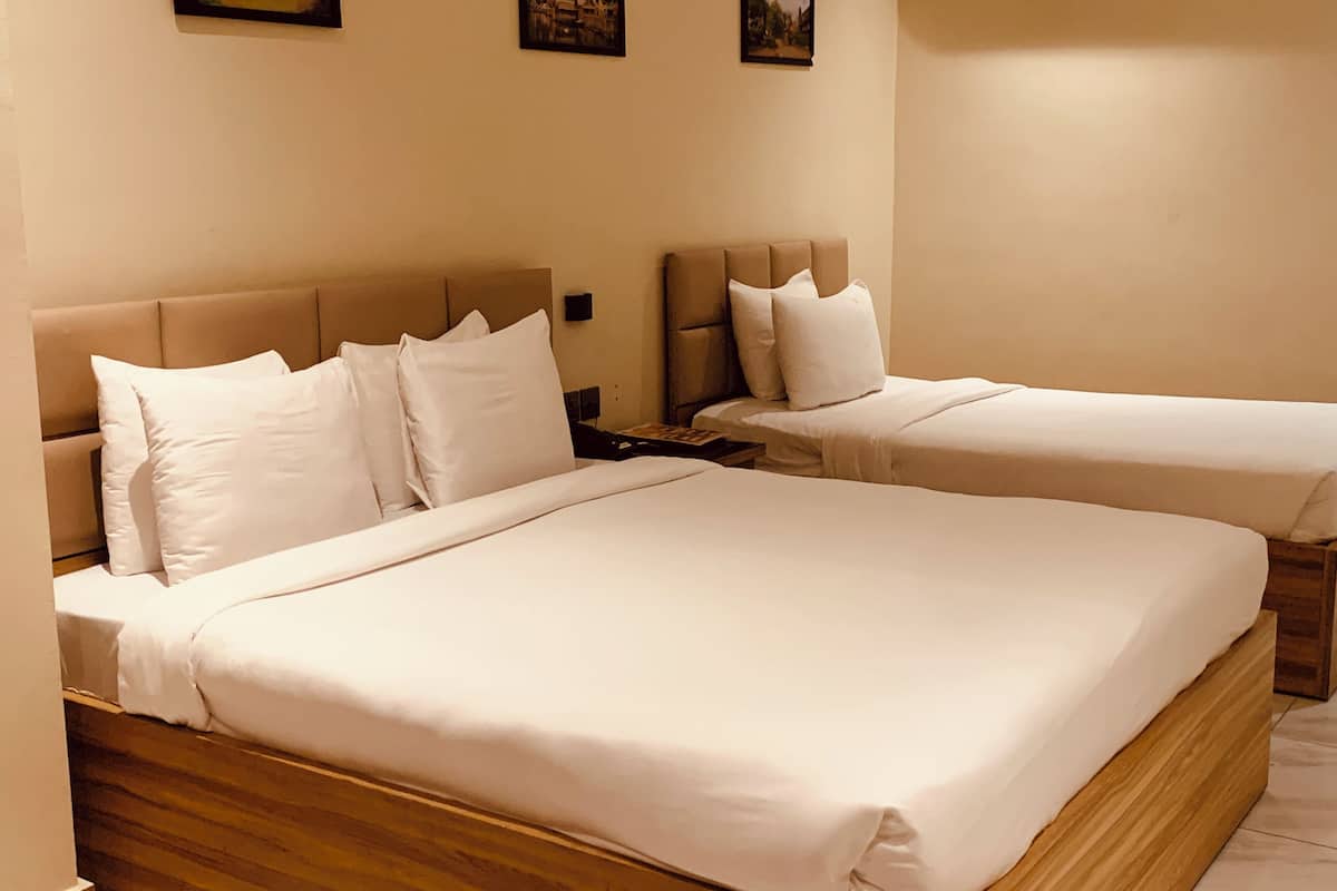 A hotel room with two beds, each with white bedding and headboards.