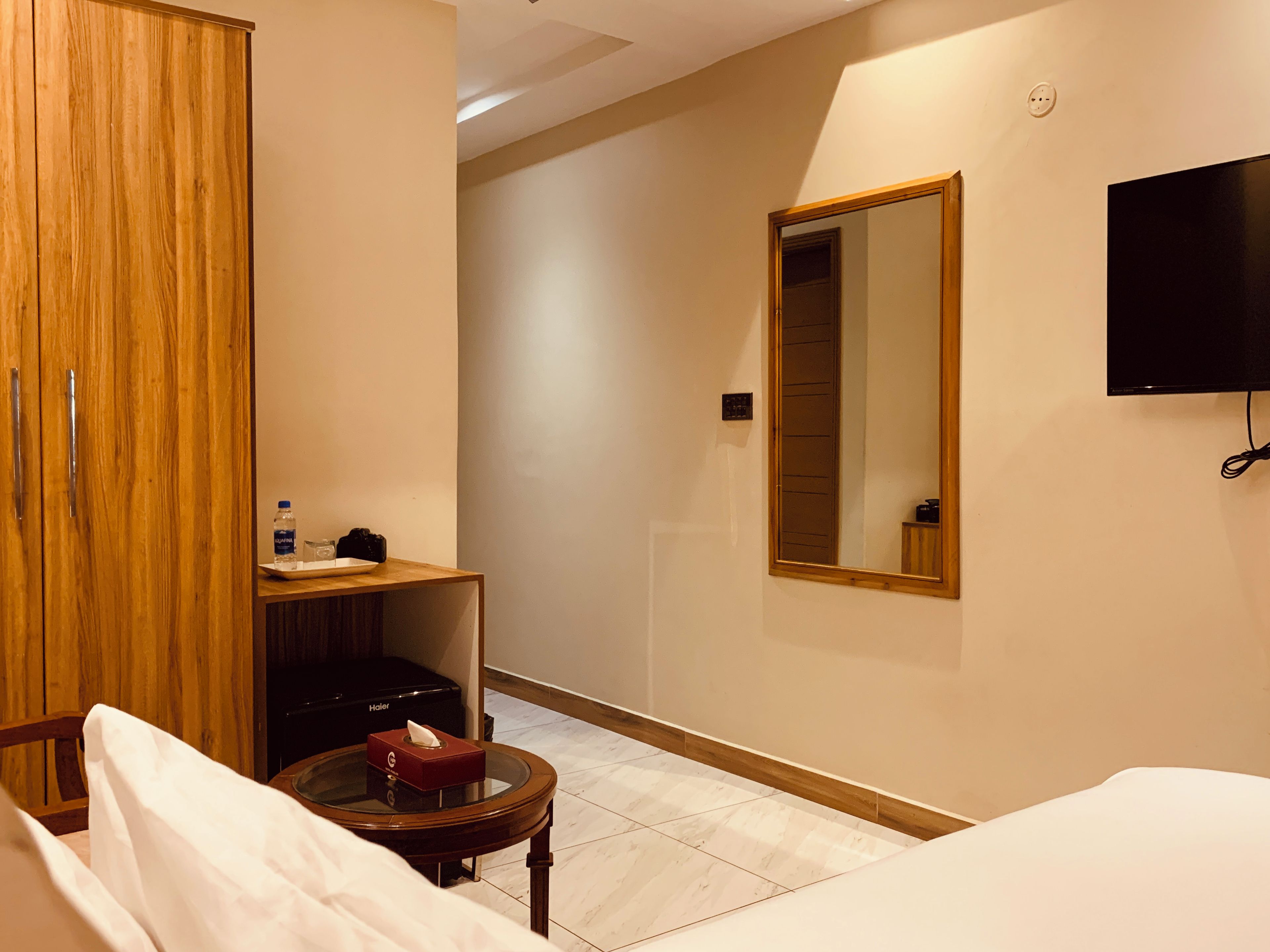 Habitación de hotel con cama, mesita de noche, espejo, armario y televisor.