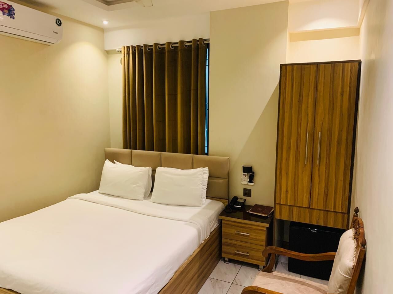 Ein Hotelzimmer mit Bett, Nachttisch, Fernseher und Kleiderschrank.