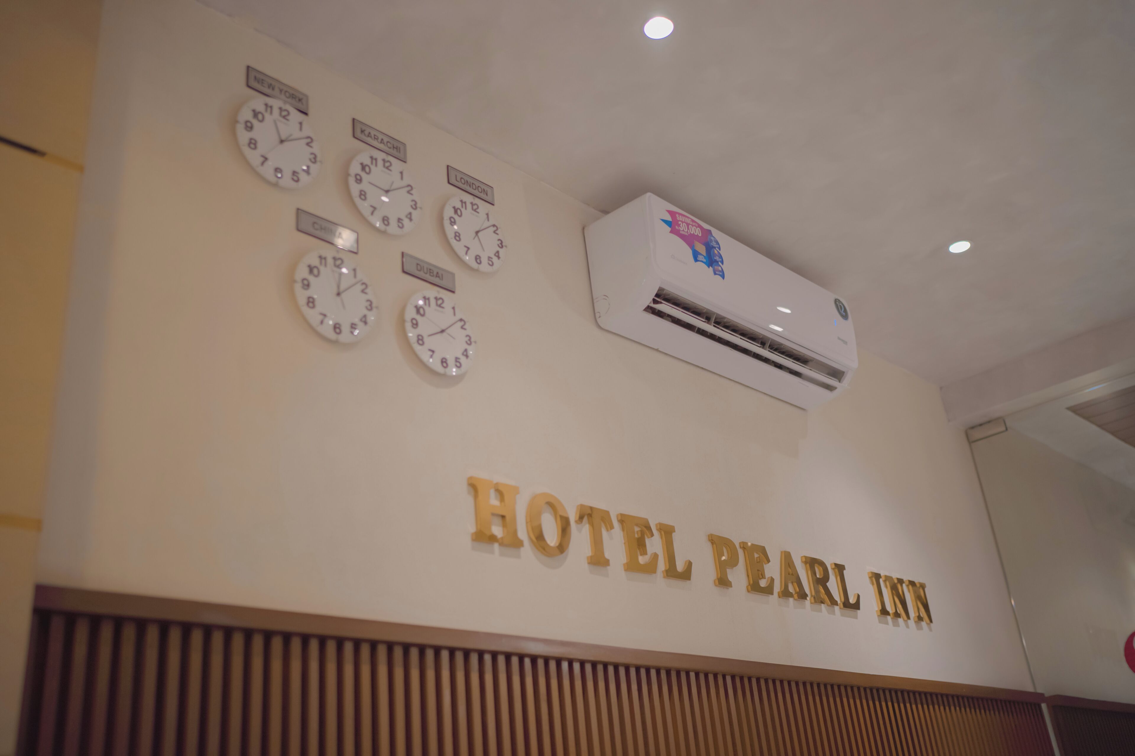 A wall with clocks labeled with city names and the text "HOTEL PEARL INN".