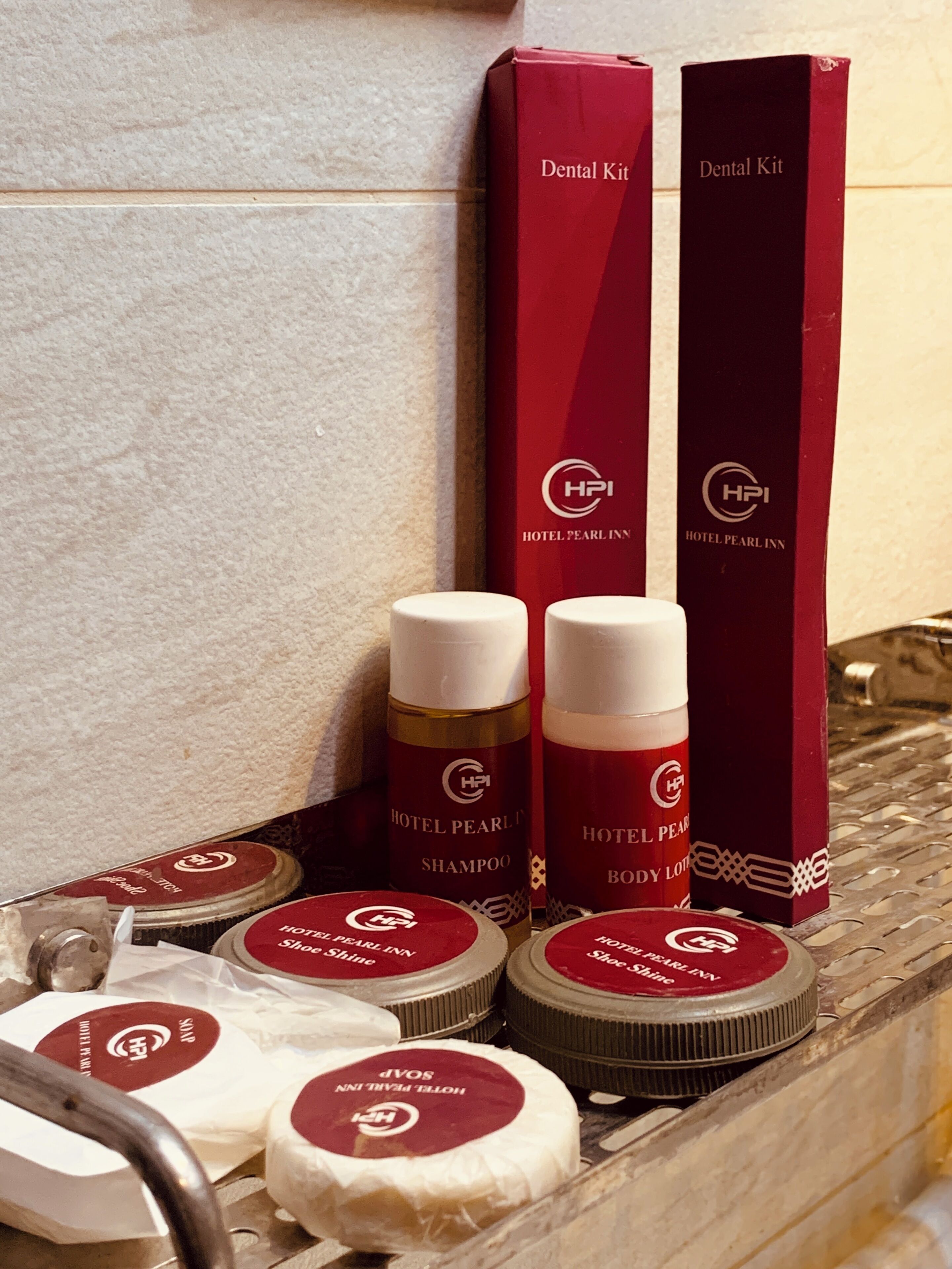 Een badkamer met een marmeren wastafel, een spiegel en toiletartikelen, waaronder een tandverzorgingsset, bodylotion en schoenschoonmaakproducten.