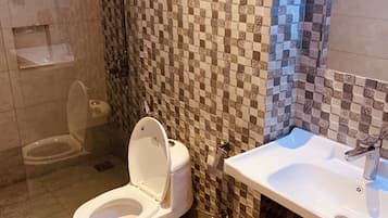 Un baño con inodoro, lavabo y zona de ducha.