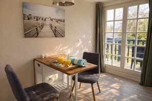 A dining area with a wooden table, two chairs, and a painting of a desert scene.