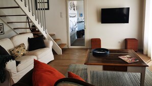 A living room with a staircase, a sofa, a coffee table, and a television.