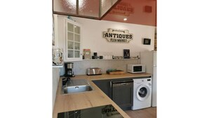 A compact kitchen with a sink, toaster, microwave, and washing machine.