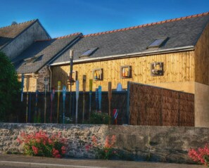A wooden building with a stone wall and a metal fence. - Gite de la Baleine with Jacuzzi in La Turballe (La Turballe)