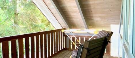 A wooden deck with a railing, a table, and two chairs.