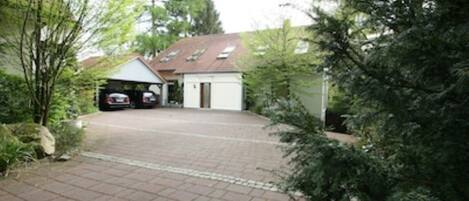 Ein gepflasterter Weg führt zu einer Garage, in der zwei Autos stehen.