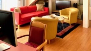 Una sala de estar moderna con un sofá rojo, un sillón amarillo y un televisor de pantalla plana.