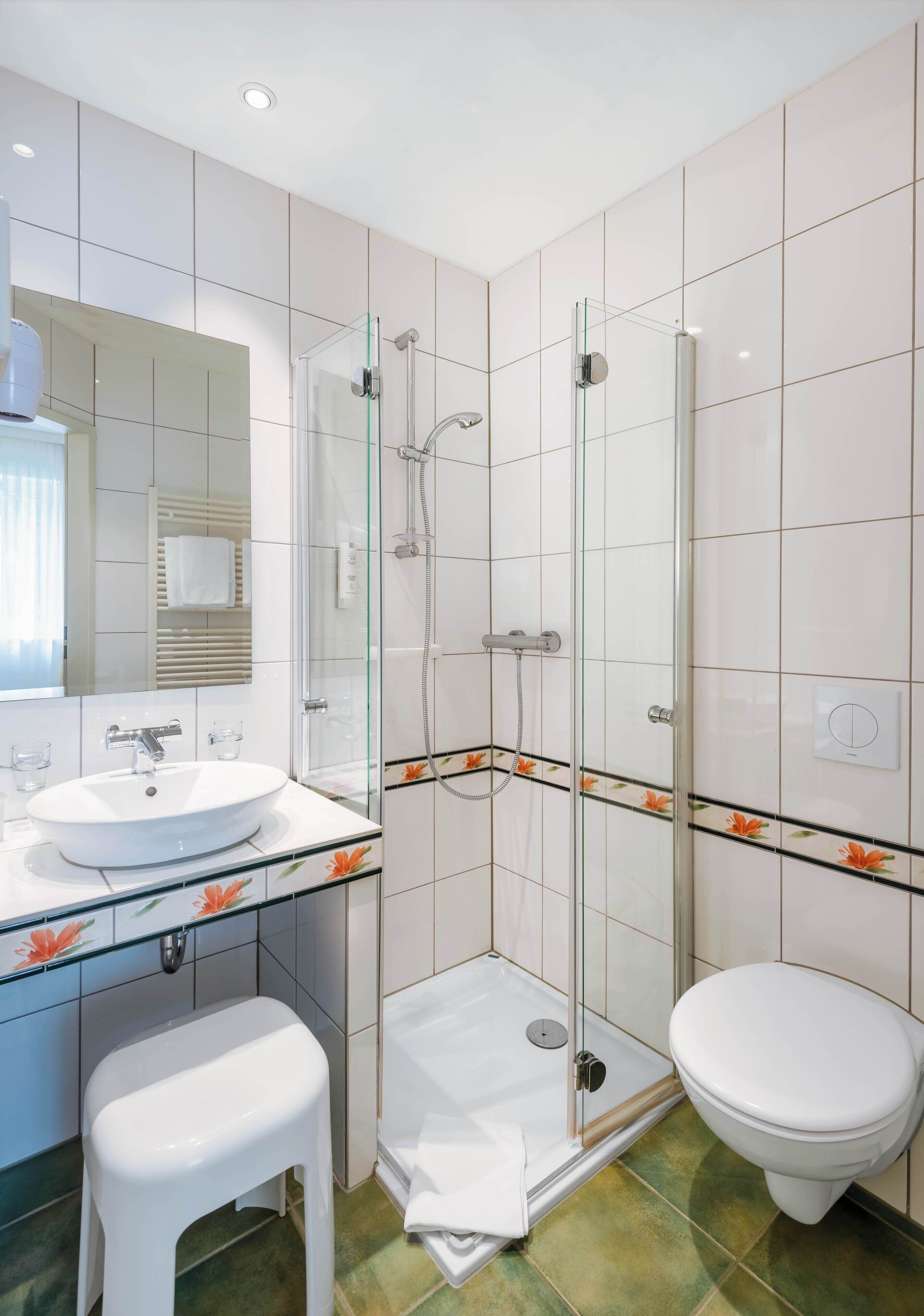 A modern bathroom with a glass-enclosed shower, a white sink, and a toilet.
